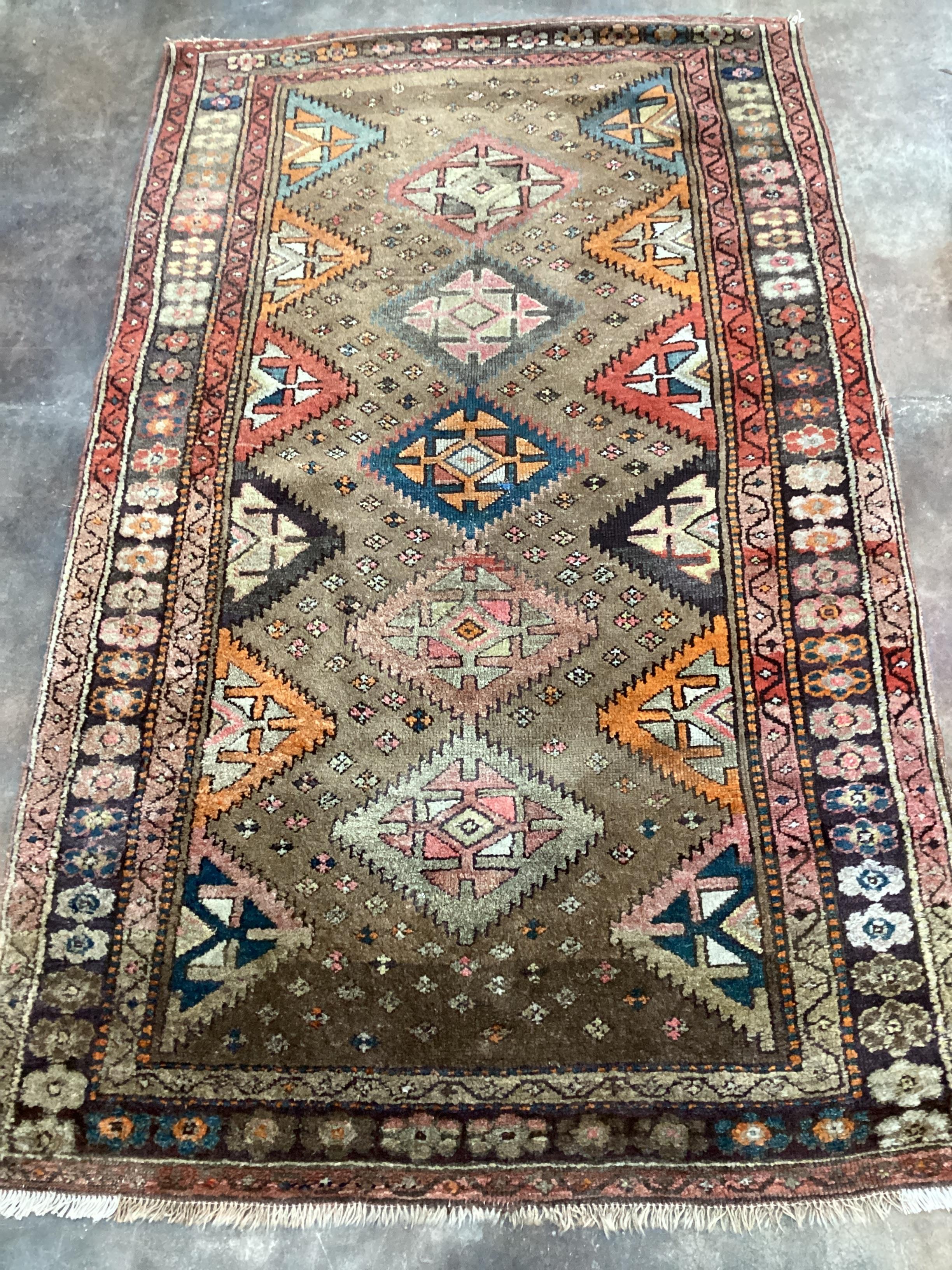 A Caucasian rug with geometric motifs on brown ground, 200 x 122cm